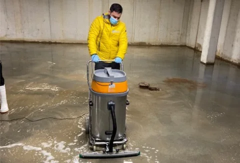Een man die met een industriële stofzuiger een bouwplaats reinigt.
